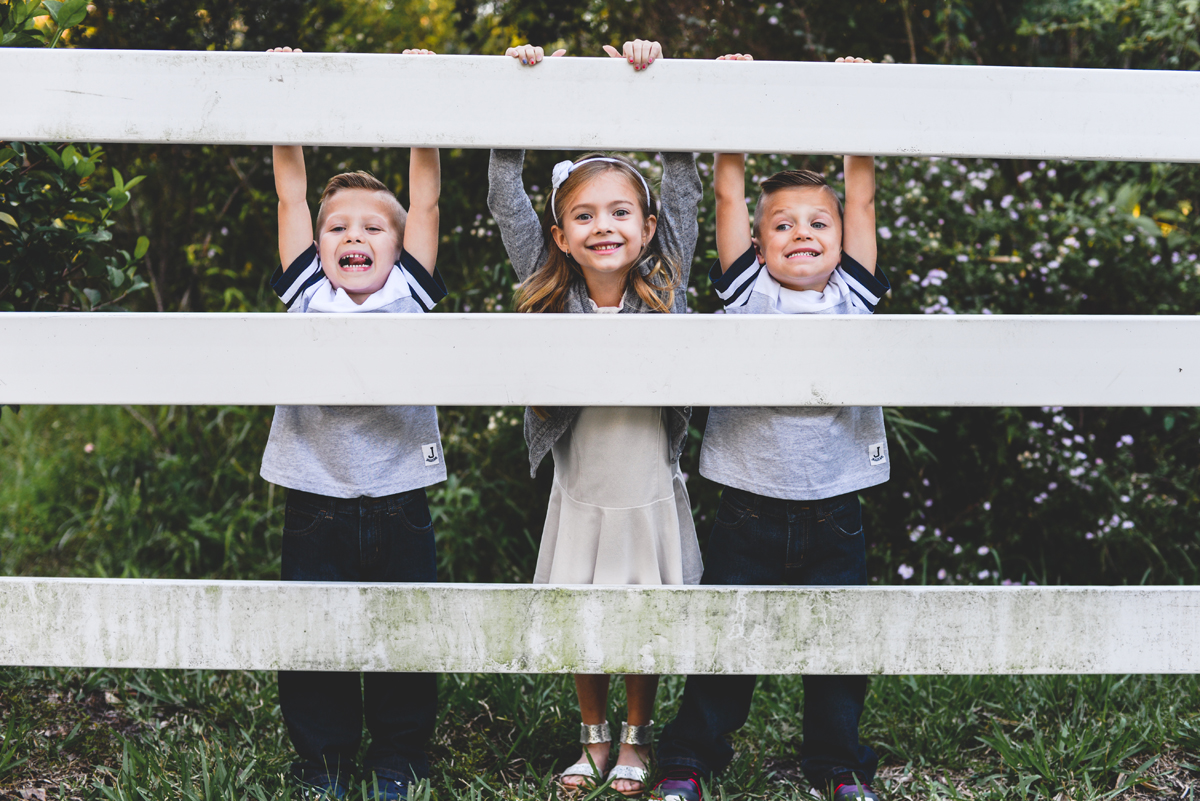 fence, grass, kids, playing, siblings, smiles