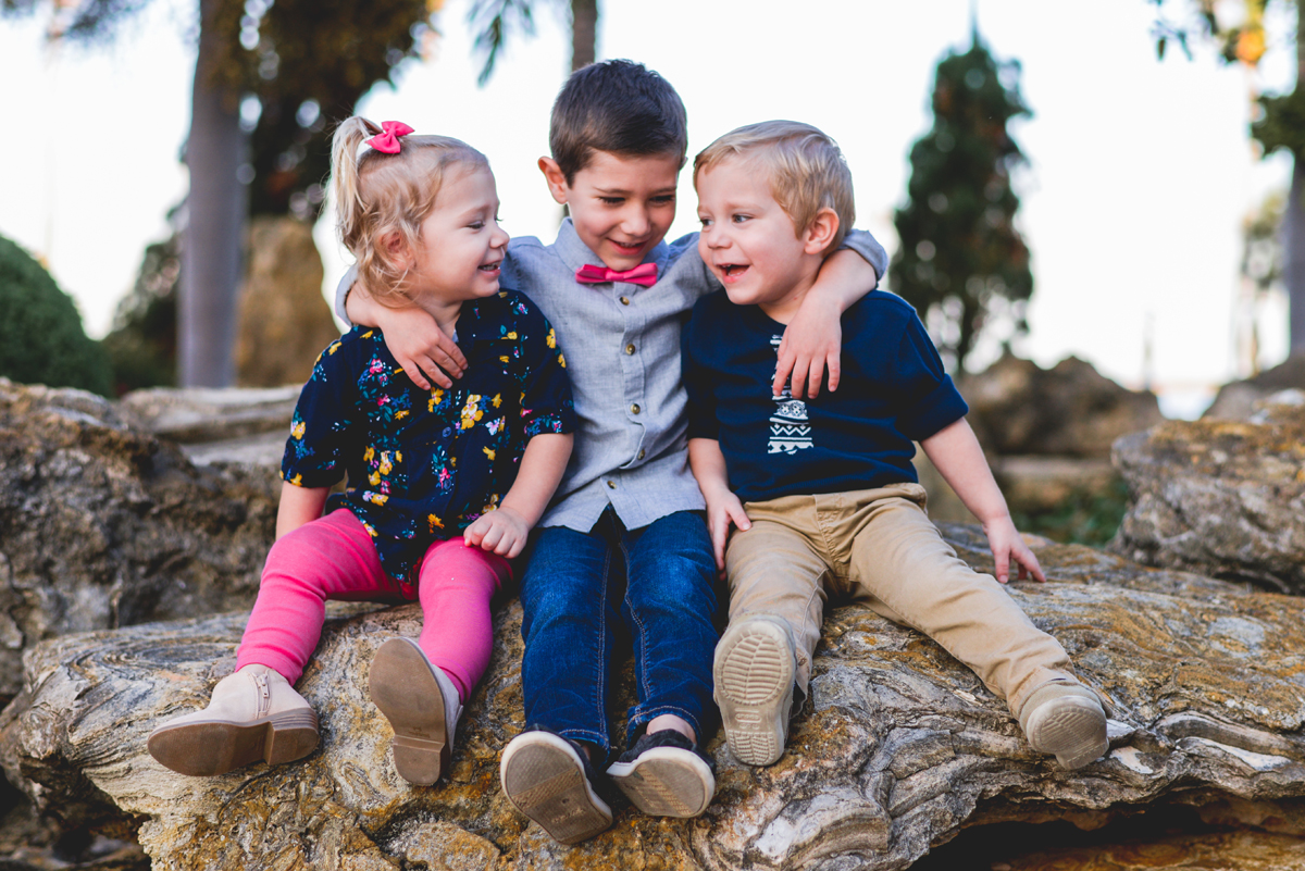 siblings, hugging, laughing, sitting, rock, trees